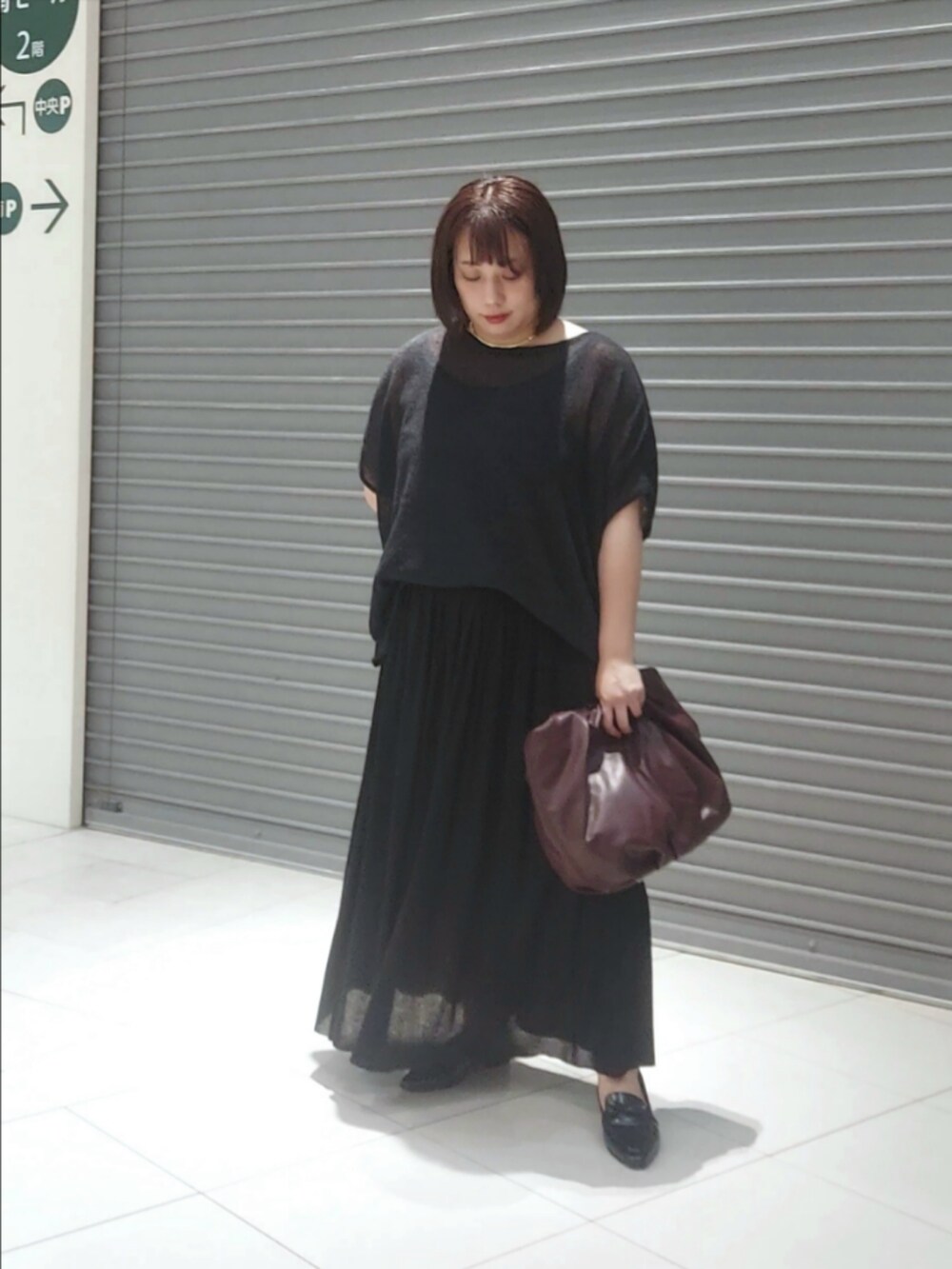 ブラック系のニット/セーター、ブラック系のスカート、ブラウン系のショルダーバッグを着用したレディースの秋コーディネートの3枚目の写真