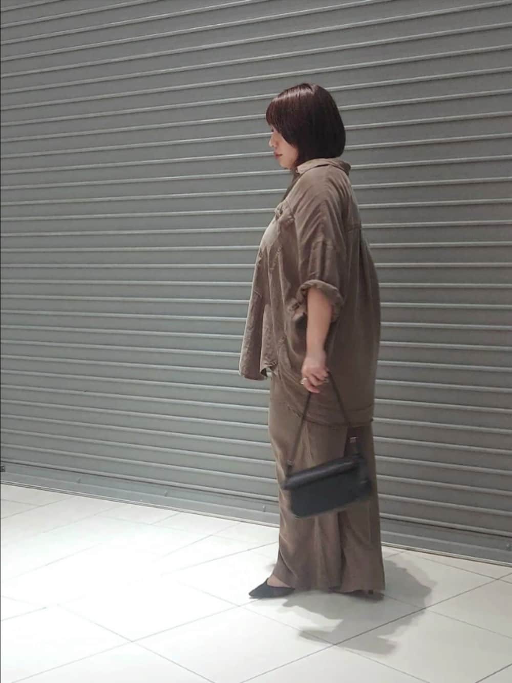ブラウン系のシャツ/ブラウス、グレー系のその他パンツ、ブラック系のパンプスを着用したレディースの夏コーディネートの3枚目の写真