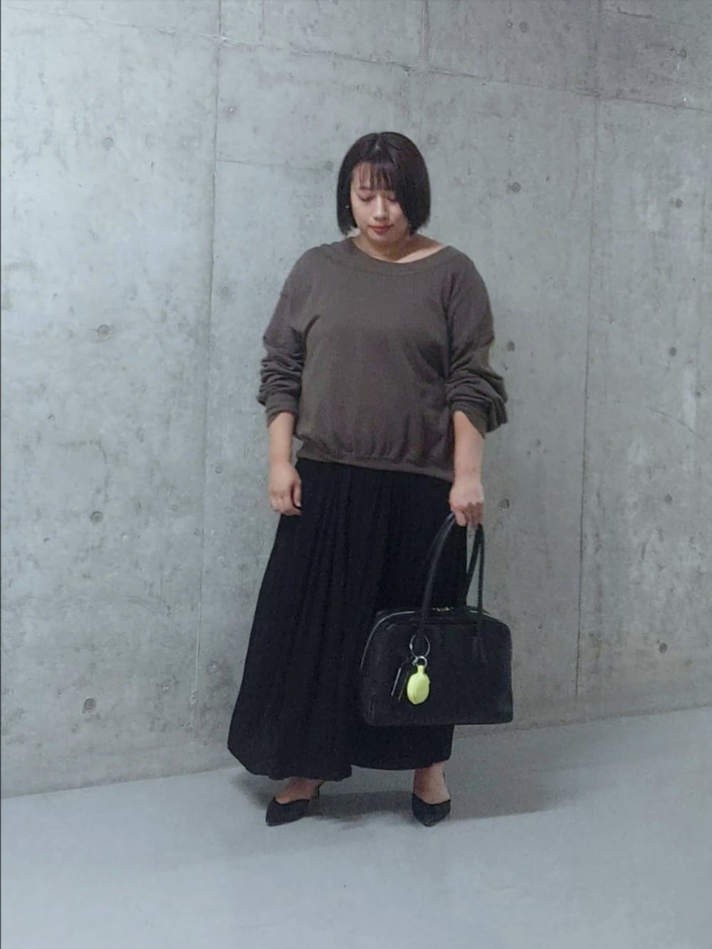 ブラック系のスウェット、ブラック系のスカート、ブラック系のパンプスを着用したレディースの秋コーディネートの3枚目の写真