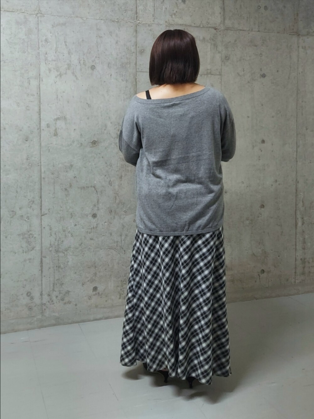 ブラック系のニット/セーター、ブラック系のスカート、ブラック系のパンプスを着用したレディースの夏コーディネートの2枚目の写真