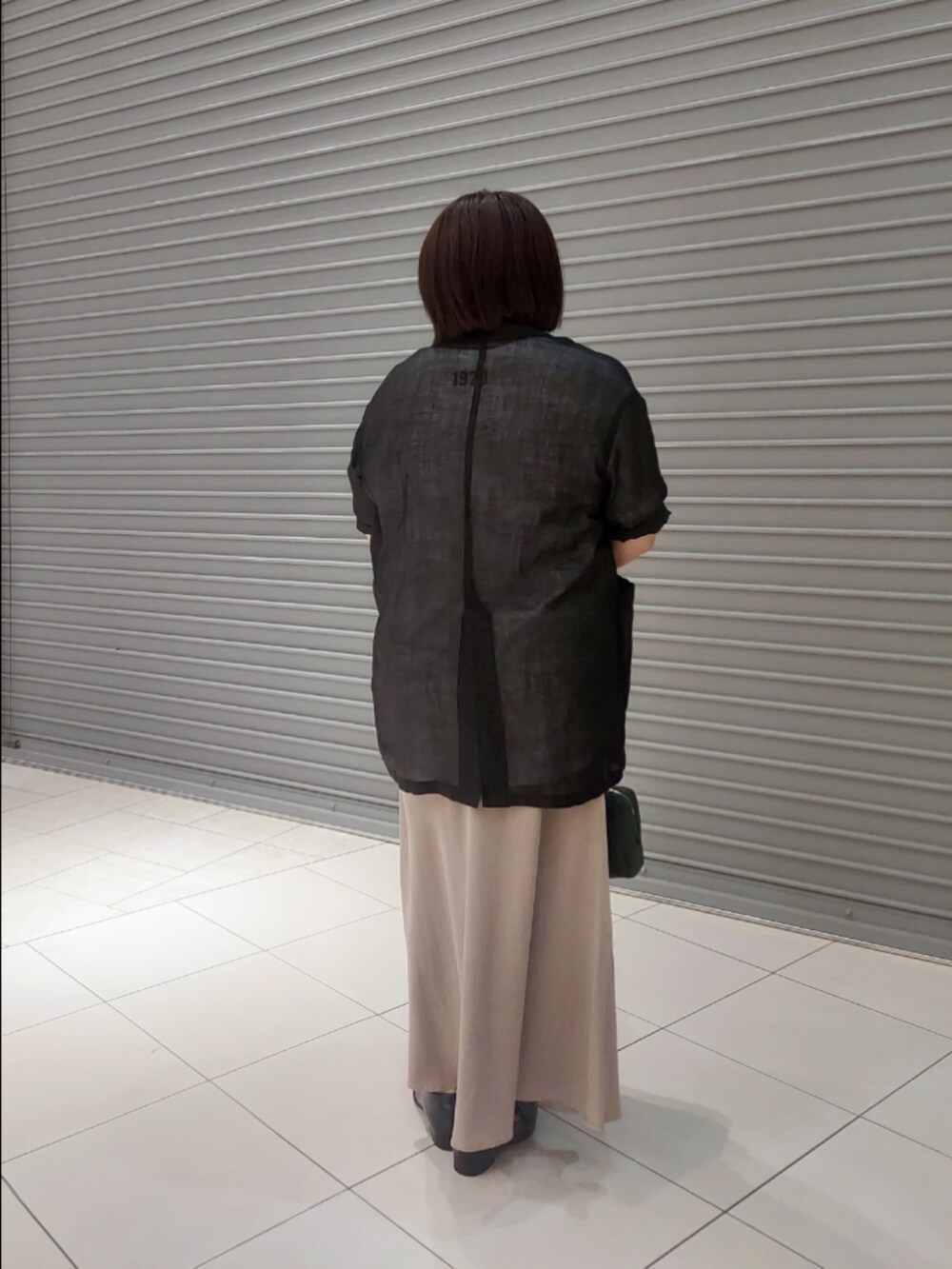 ブラック系のテーラードジャケット、ホワイト系のTシャツ/カットソー、グレー系のスカートを着用したレディースの夏コーディネートの2枚目の写真