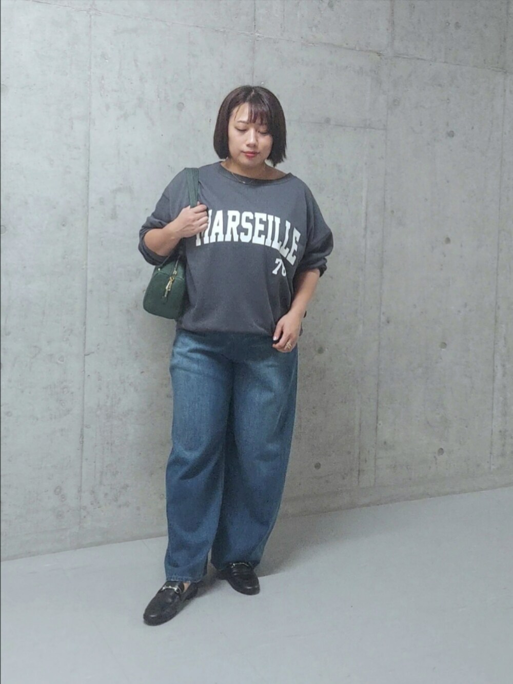 グレー系のスウェット、ブルー系のデニムパンツ、ブラック系のローファーを着用したレディースの秋コーディネートの2枚目の写真
