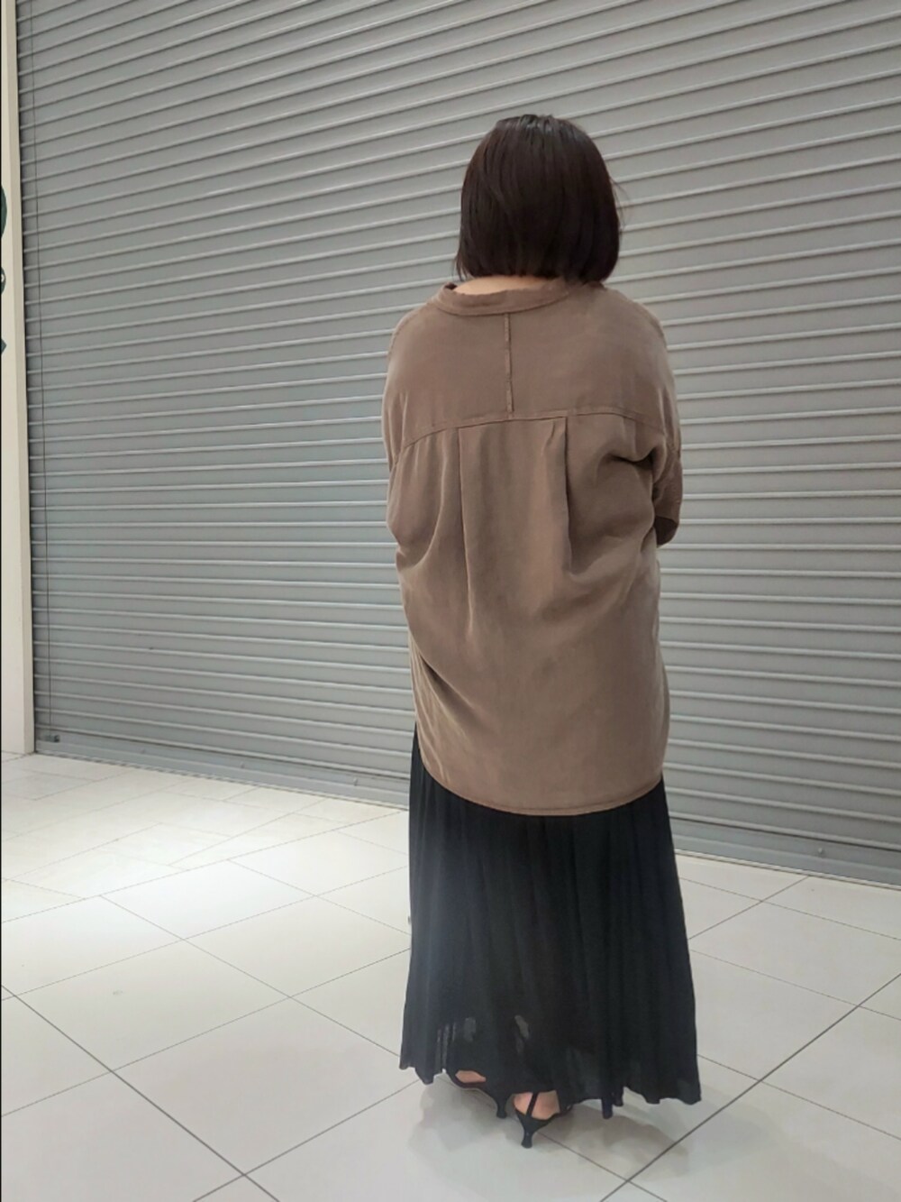 ブラウン系のシャツ/ブラウス、ブラック系のパンプス、ブラック系のスカートを着用したレディースの夏コーディネートの3枚目の写真