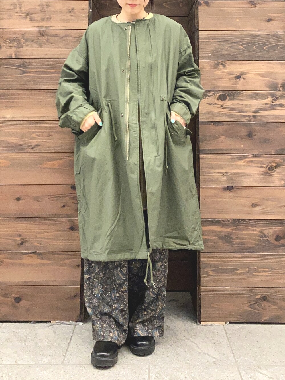 ブラック系のその他パンツ、ベージュ系のモッズコート、イエロー系のカーディガン/ボレロを着用したレディースの冬コーディネートの2枚目の写真