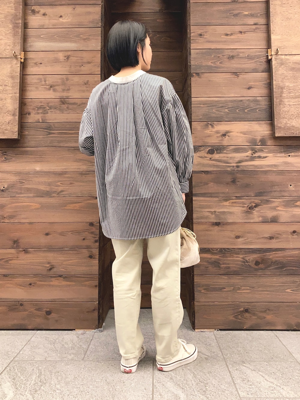 グリーン系のトレンチコート、ブラック系のシャツ/ブラウス、ホワイト系のスニーカーを着用したレディースの春コーディネートの3枚目の写真