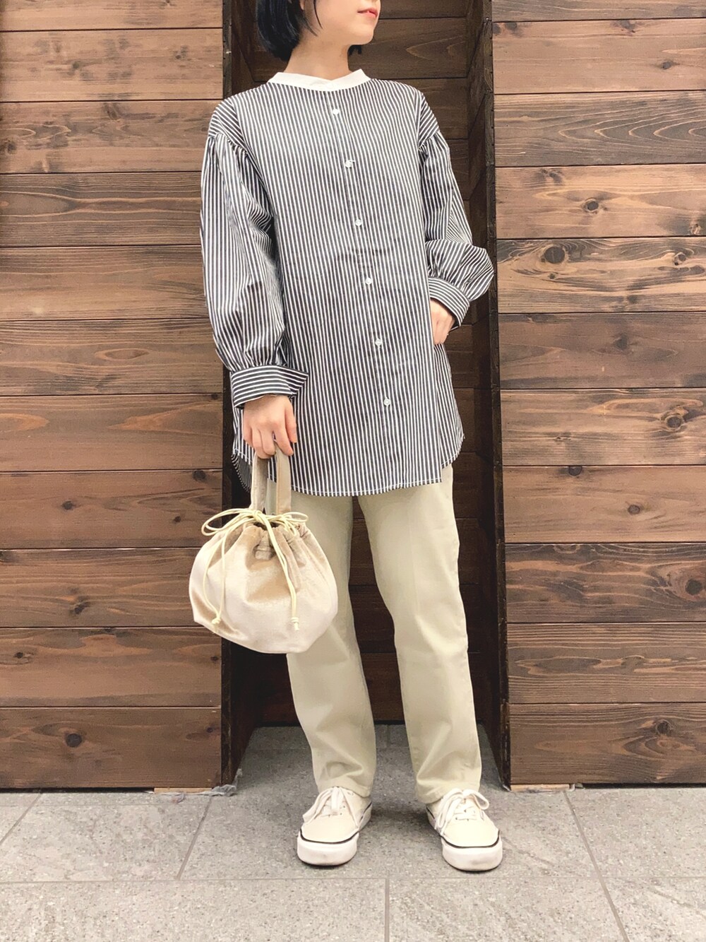 グリーン系のトレンチコート、ブラック系のシャツ/ブラウス、ホワイト系のスニーカーを着用したレディースの春コーディネートの2枚目の写真