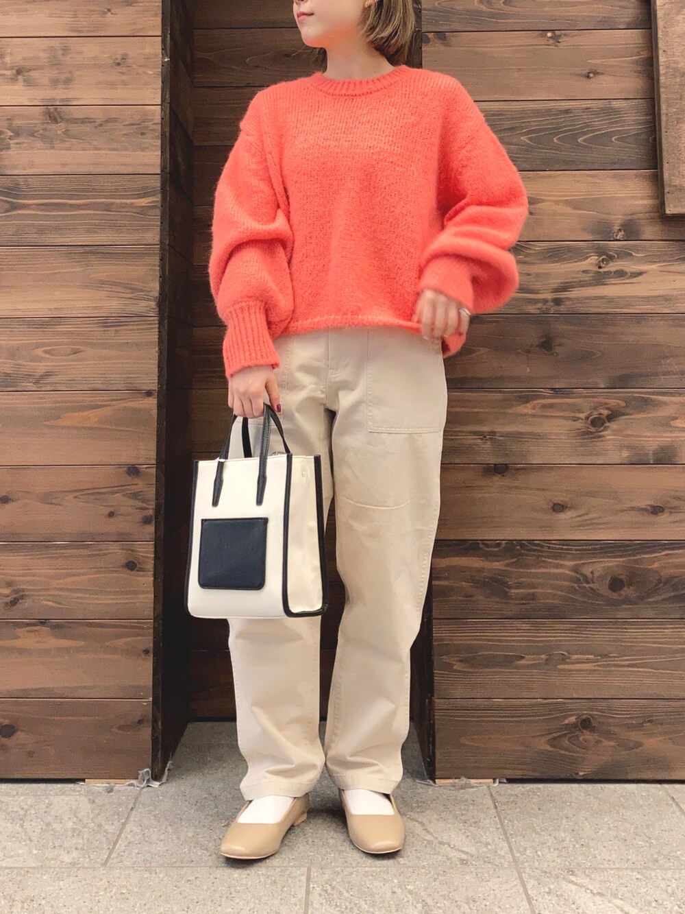 ブラック系のブルゾン、オレンジ系のニット/セーター、ホワイト系のその他パンツを着用したレディースの冬コーディネートの2枚目の写真