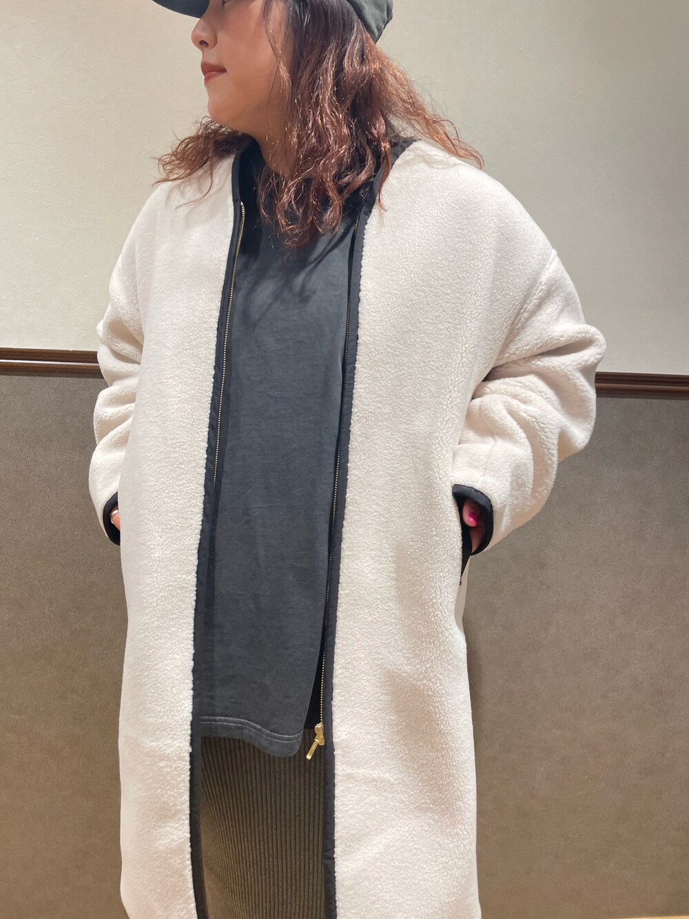 ホワイト系のノーカラーコート、グレー系のスカート、ブラック系のその他シューズを着用したレディースの冬コーディネートの3枚目の写真