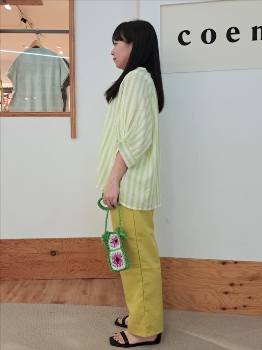 グリーン系のシャツ/ブラウス、イエロー系のスラックス、ホワイト系のタンクトップを着用したレディースの春コーディネートの3枚目の写真