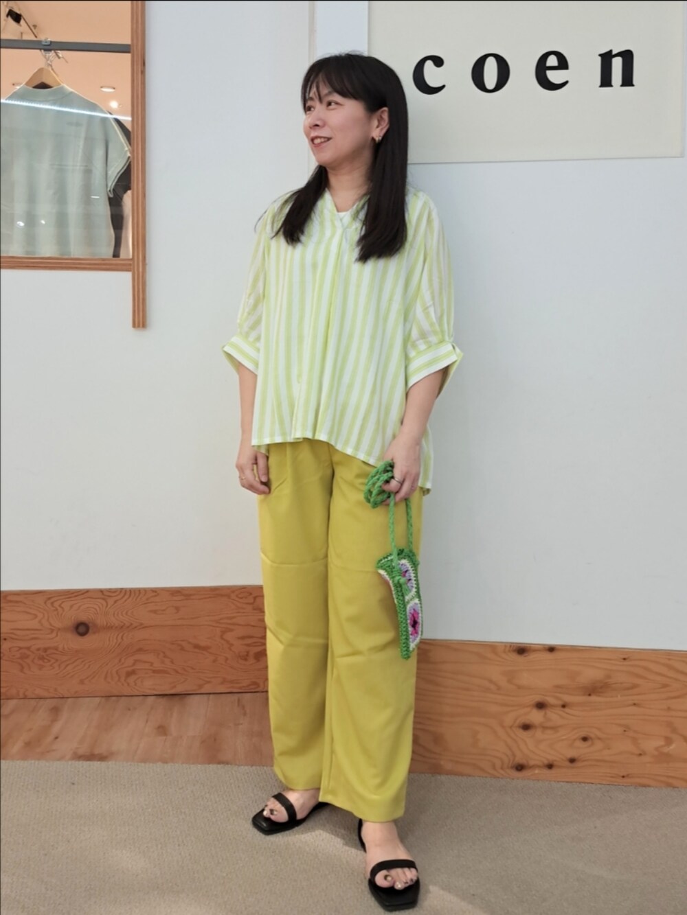 グリーン系のシャツ/ブラウス、イエロー系のスラックス、ホワイト系のタンクトップを着用したレディースの春コーディネートの2枚目の写真