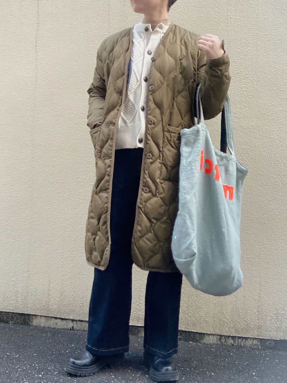 グリーン系のダウンジャケット/コート、グレー系のトートバッグ、ブルー系のスラックスを着用したレディースの冬コーディネートの2枚目の写真