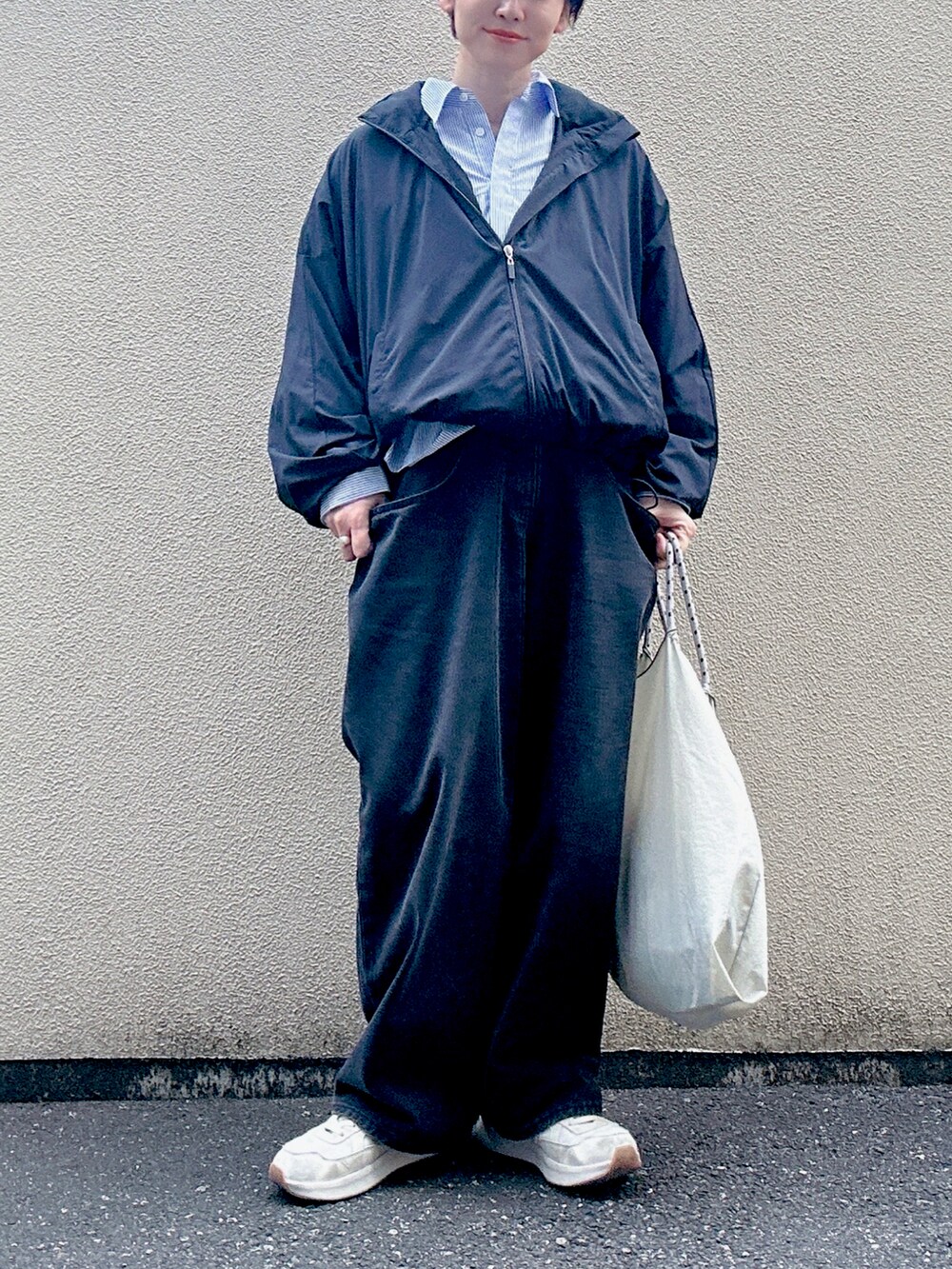 ブラック系のデニムパンツ、ホワイト系のスニーカー、ブラック系のブルゾンを着用したレディースの秋コーディネートの2枚目の写真