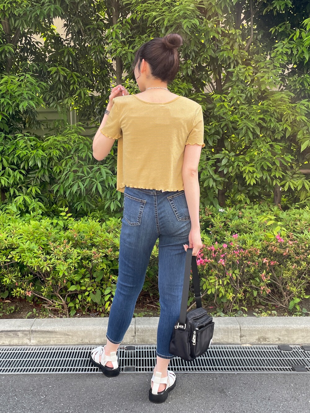 イエロー系のアンサンブル、ブルー系のデニムパンツ、ホワイト系のサンダルを着用したレディースの夏コーディネートの3枚目の写真