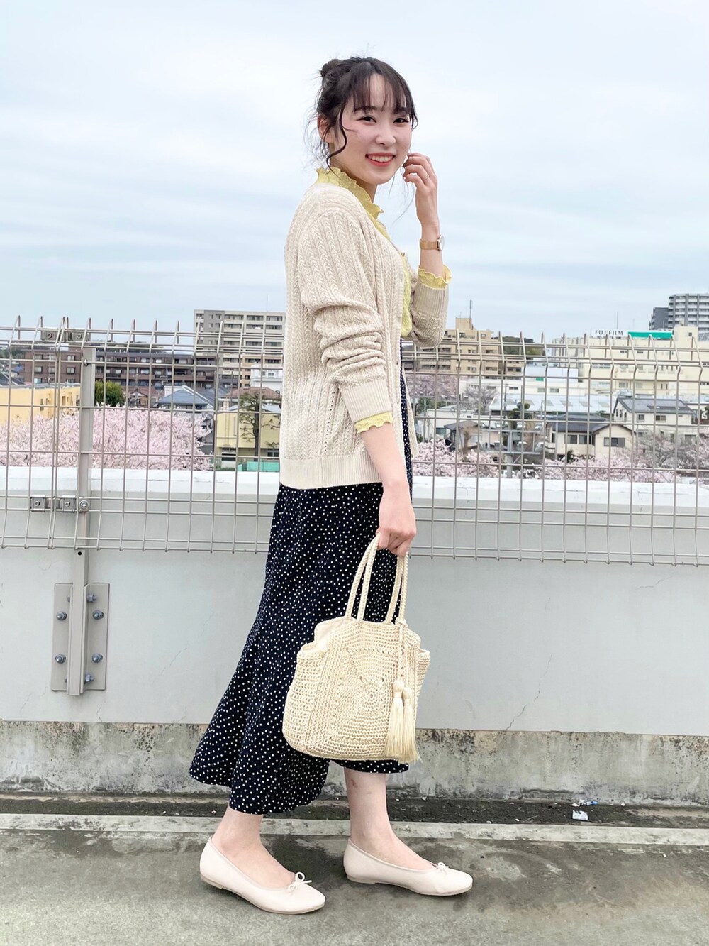ホワイト系のカーディガン/ボレロ、イエロー系のTシャツ/カットソー、ブラック系のスカートを着用したレディースの春コーディネートの2枚目の写真