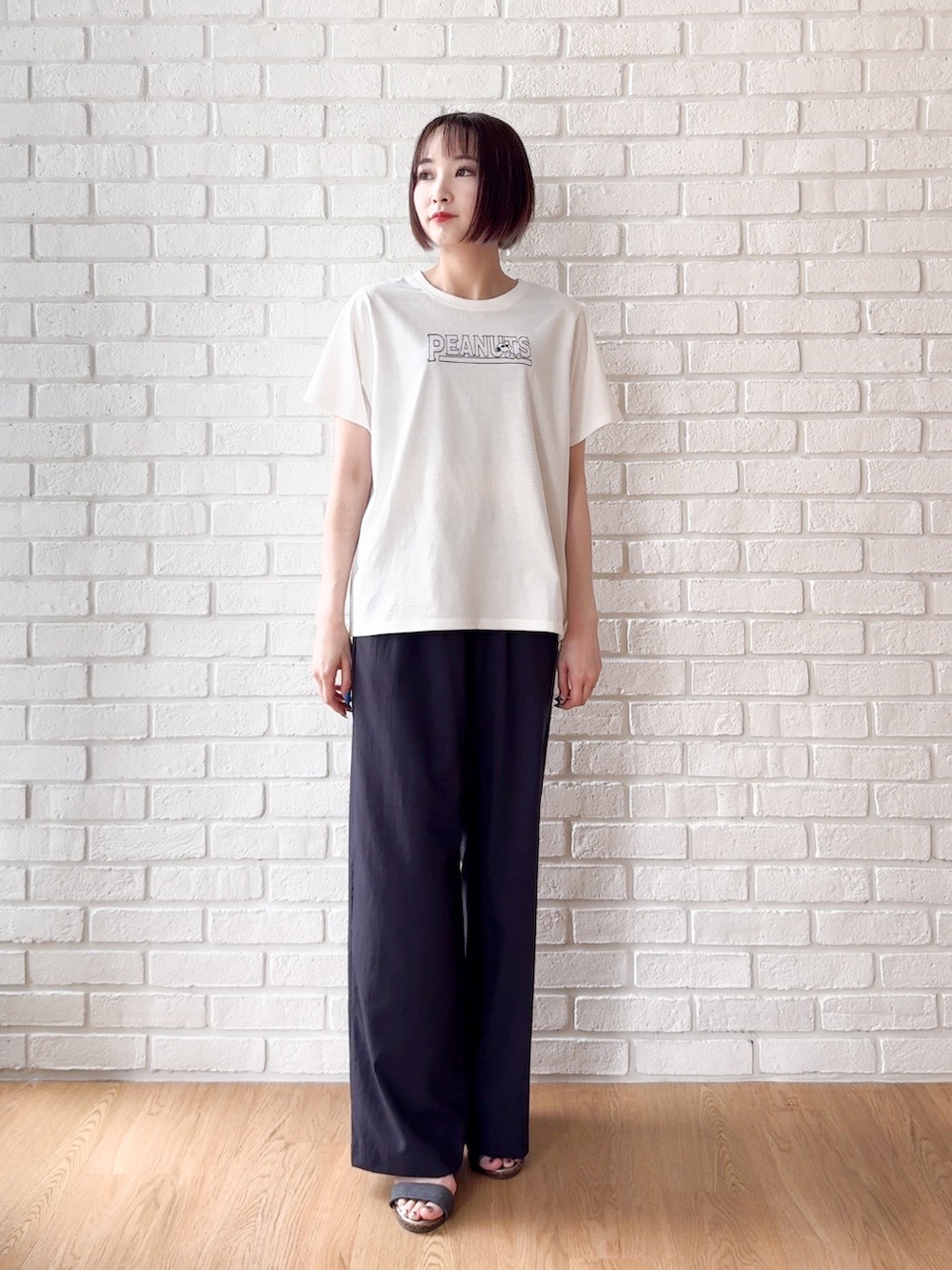 ホワイト系のTシャツ/カットソー、ブラック系のサンダル、ブラック系のトートバッグを着用したレディースの夏コーディネートの5枚目の写真