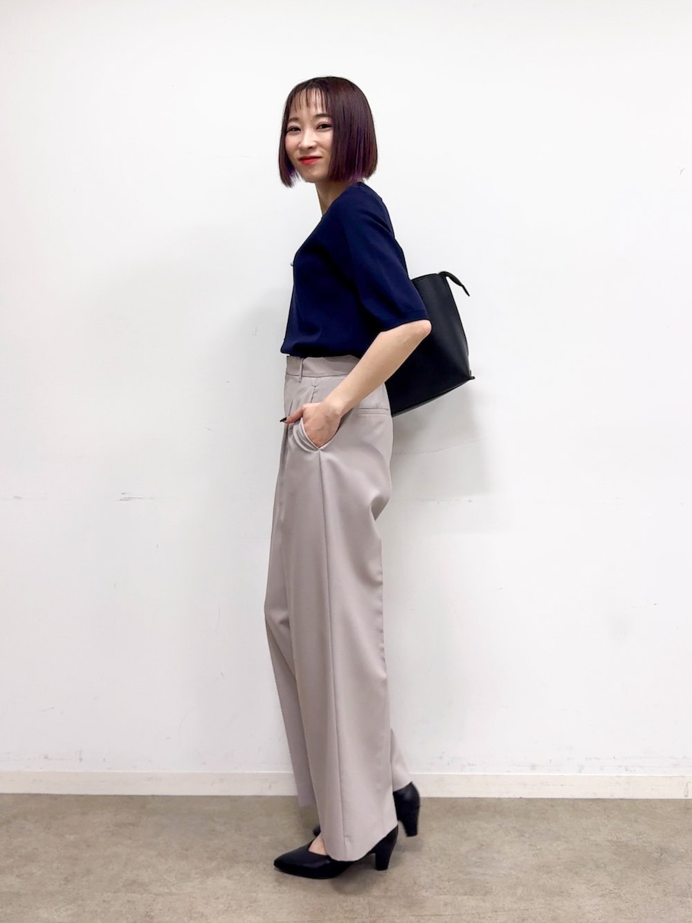 ブルー系のニット/セーター、ベージュ系のその他パンツ、ブラック系のパンプスを着用したレディースの春コーディネートの2枚目の写真