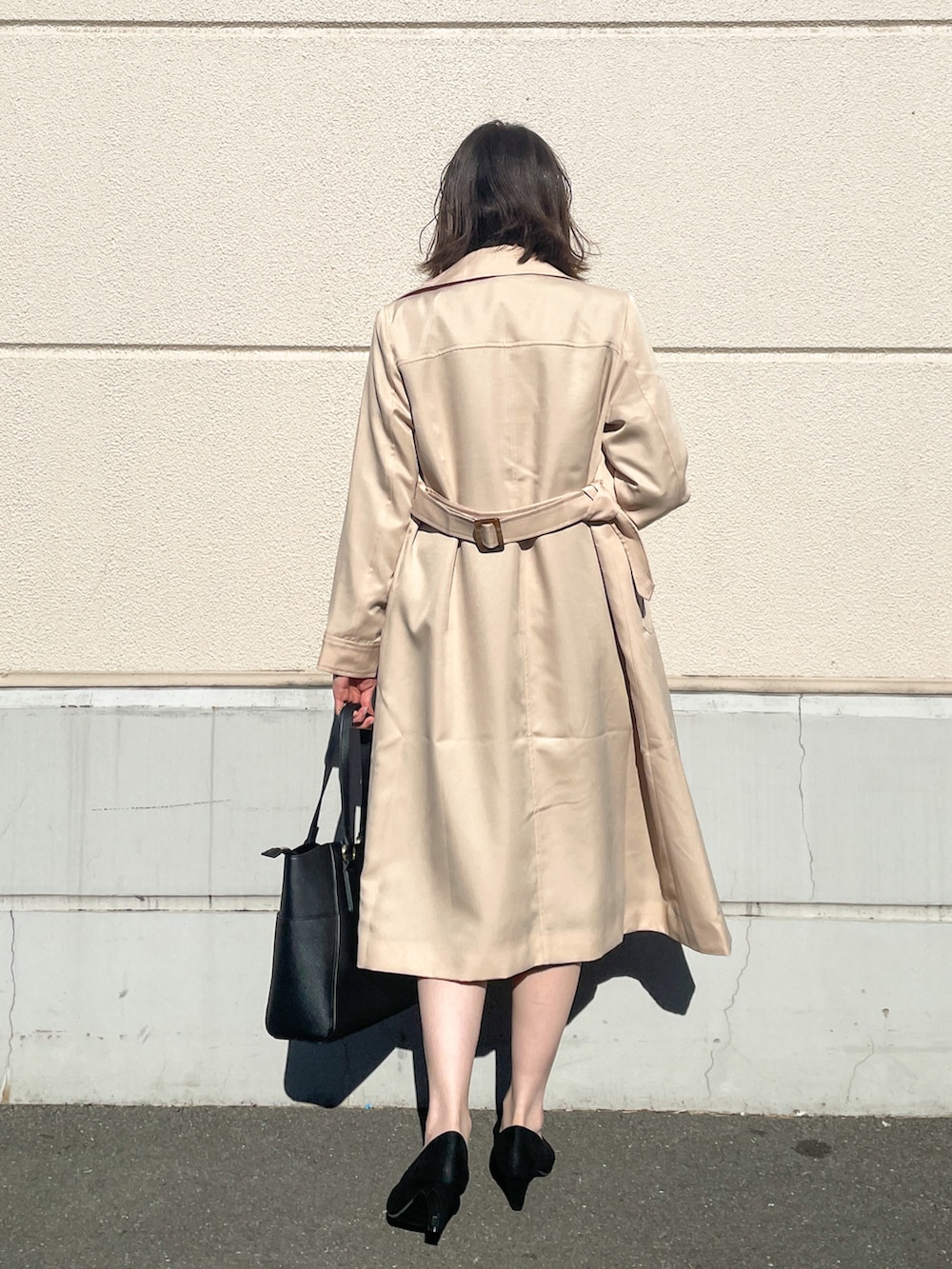 ベージュ系のトレンチコート、ブラック系のノーカラージャケット、ブラック系のスカートを着用したレディースの冬コーディネートの3枚目の写真