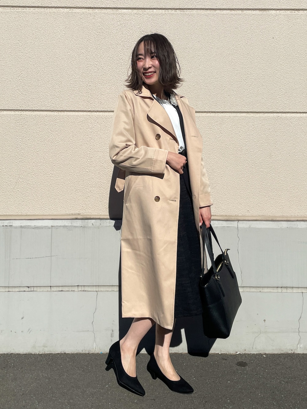 ベージュ系のトレンチコート、ブラック系のノーカラージャケット、ブラック系のスカートを着用したレディースの冬コーディネートの2枚目の写真