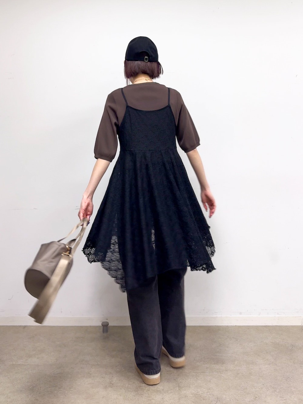 ブラウン系のニット/セーター、ブラック系のチュニック、ブラック系のデニムパンツを着用したレディースの春コーディネートの3枚目の写真