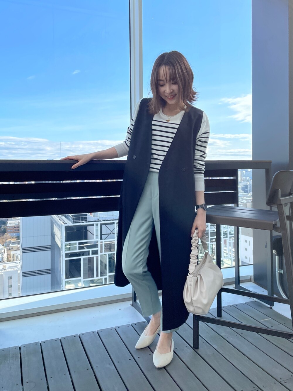 ブラック系のニット/セーター、ブラック系のベスト、ホワイト系のショルダーバッグを着用したレディースの春コーディネートの3枚目の写真