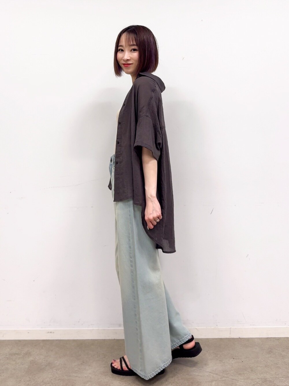 グレー系のシャツ/ブラウス、ゴールド系のタンクトップ、ブルー系のデニムパンツを着用したレディースの春コーディネートの4枚目の写真