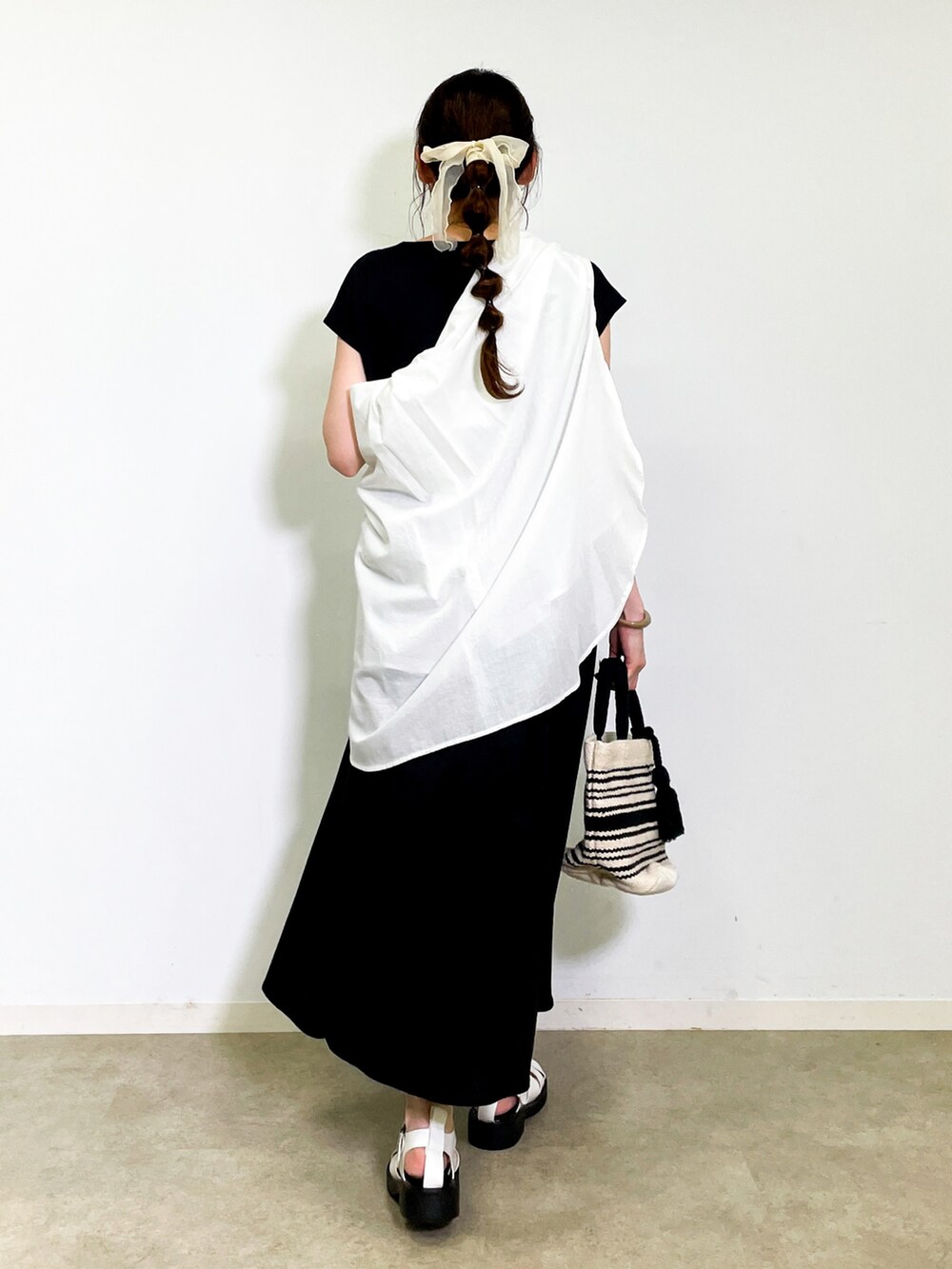 ブラック系のワンピース、ホワイト系のサンダル、ブラック系のトートバッグを着用したレディースの夏コーディネートの3枚目の写真