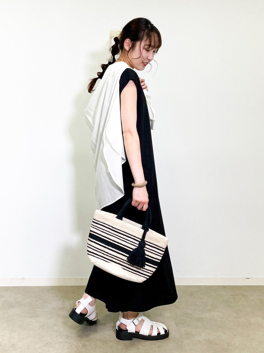 ブラック系のワンピース、ホワイト系のサンダル、ブラック系のトートバッグを着用したレディースの夏コーディネートの2枚目の写真