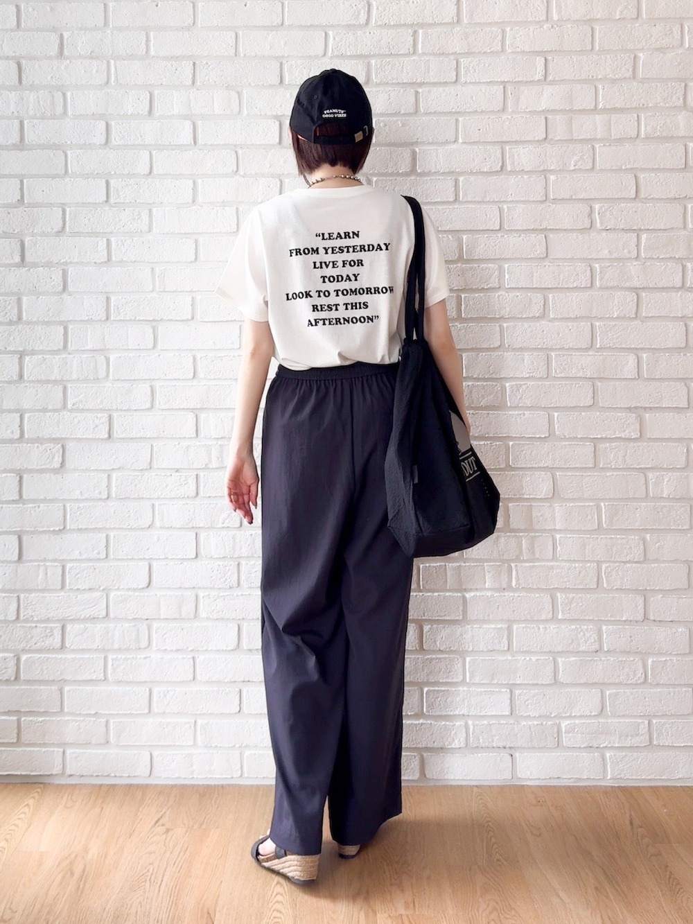ホワイト系のTシャツ/カットソー、ブラック系のサンダル、ブラック系のトートバッグを着用したレディースの夏コーディネートの3枚目の写真