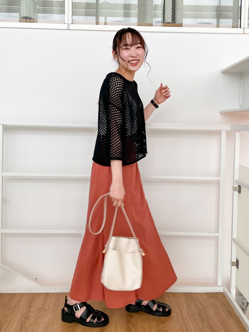 ブラック系のその他トップス、オレンジ系のスカート、ブラック系のサンダルを着用したレディースの春コーディネートの2枚目の写真