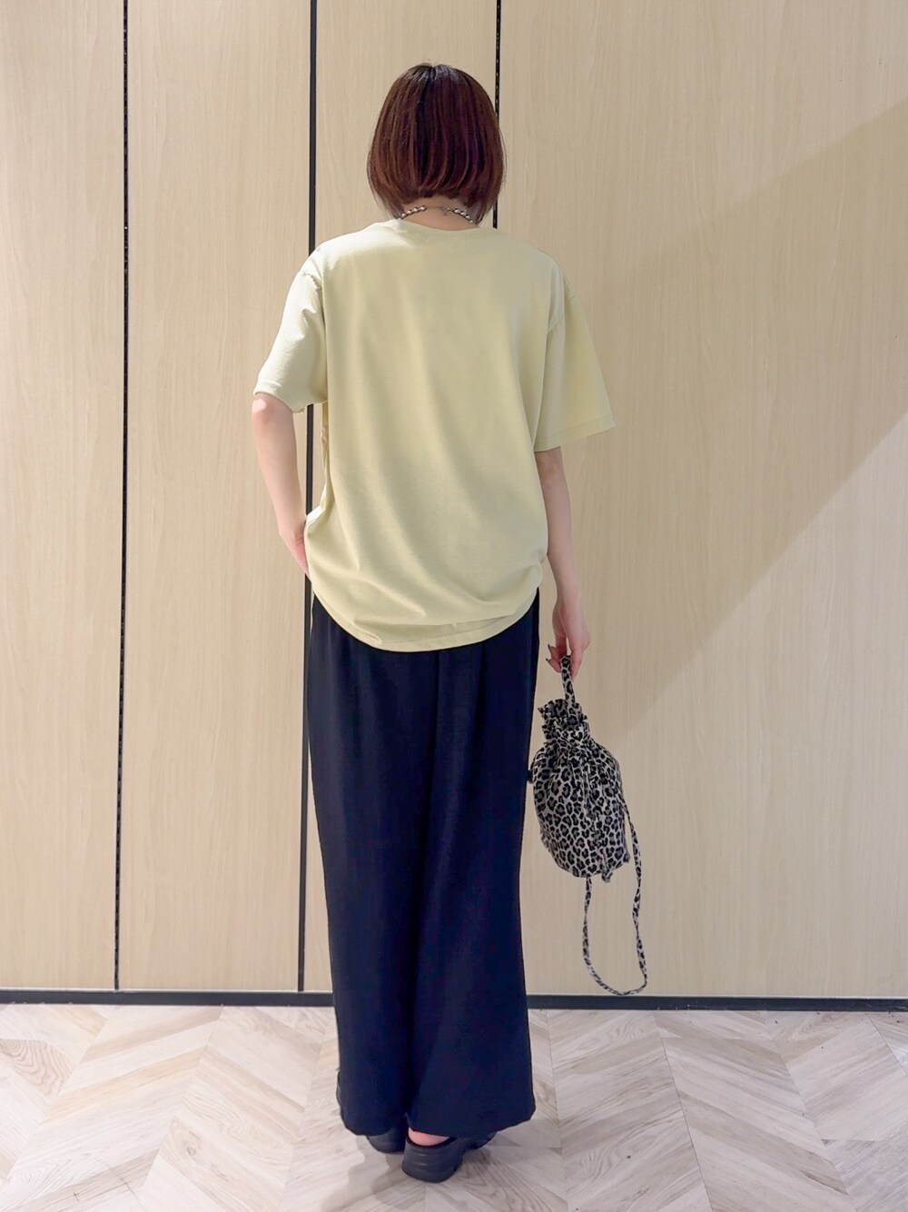 イエロー系のTシャツ/カットソー、ブラック系のサンダル、ベージュ系のショルダーバッグを着用したレディースの夏コーディネートの3枚目の写真