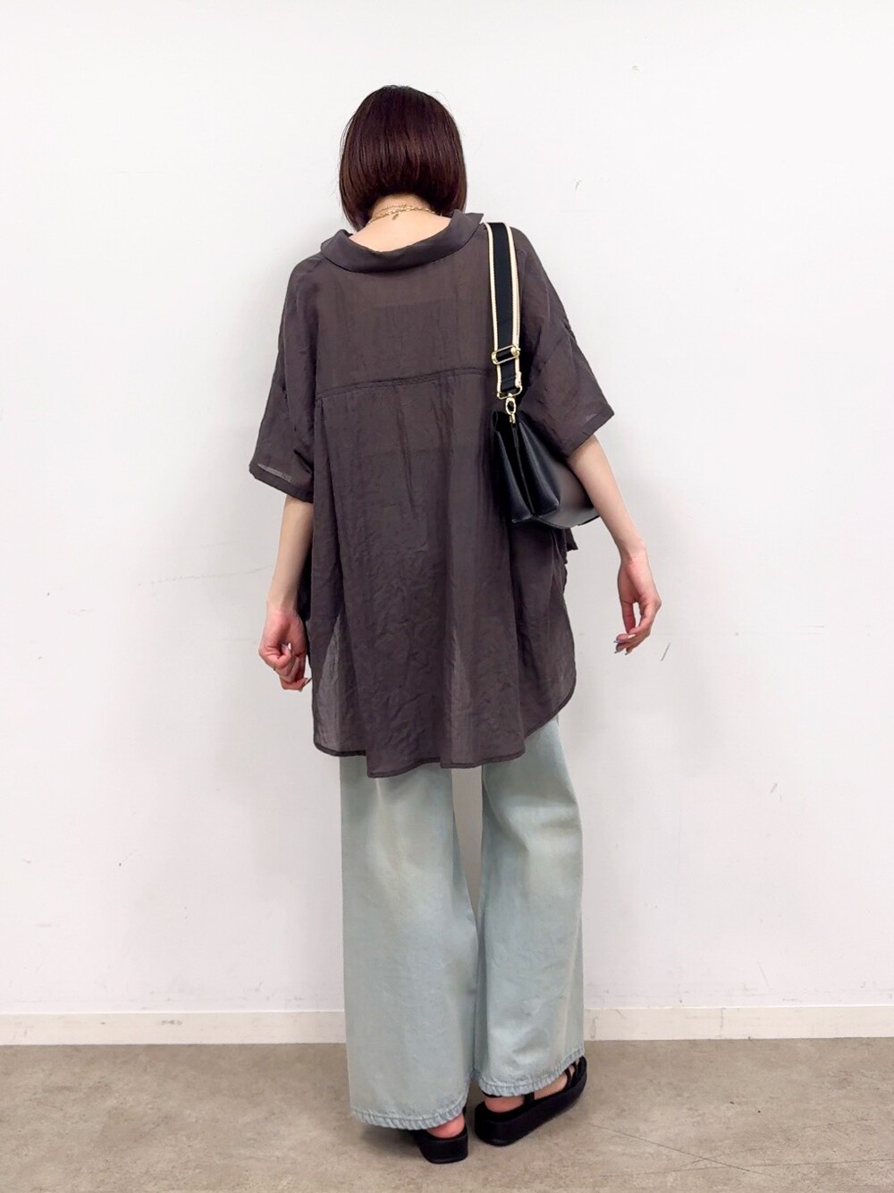グレー系のシャツ/ブラウス、ゴールド系のタンクトップ、ブルー系のデニムパンツを着用したレディースの春コーディネートの3枚目の写真