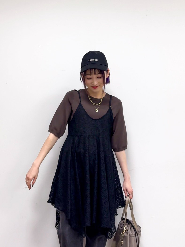 ブラウン系のニット/セーター、ブラック系のチュニック、ブラック系のデニムパンツを着用したレディースの春コーディネートの4枚目の写真