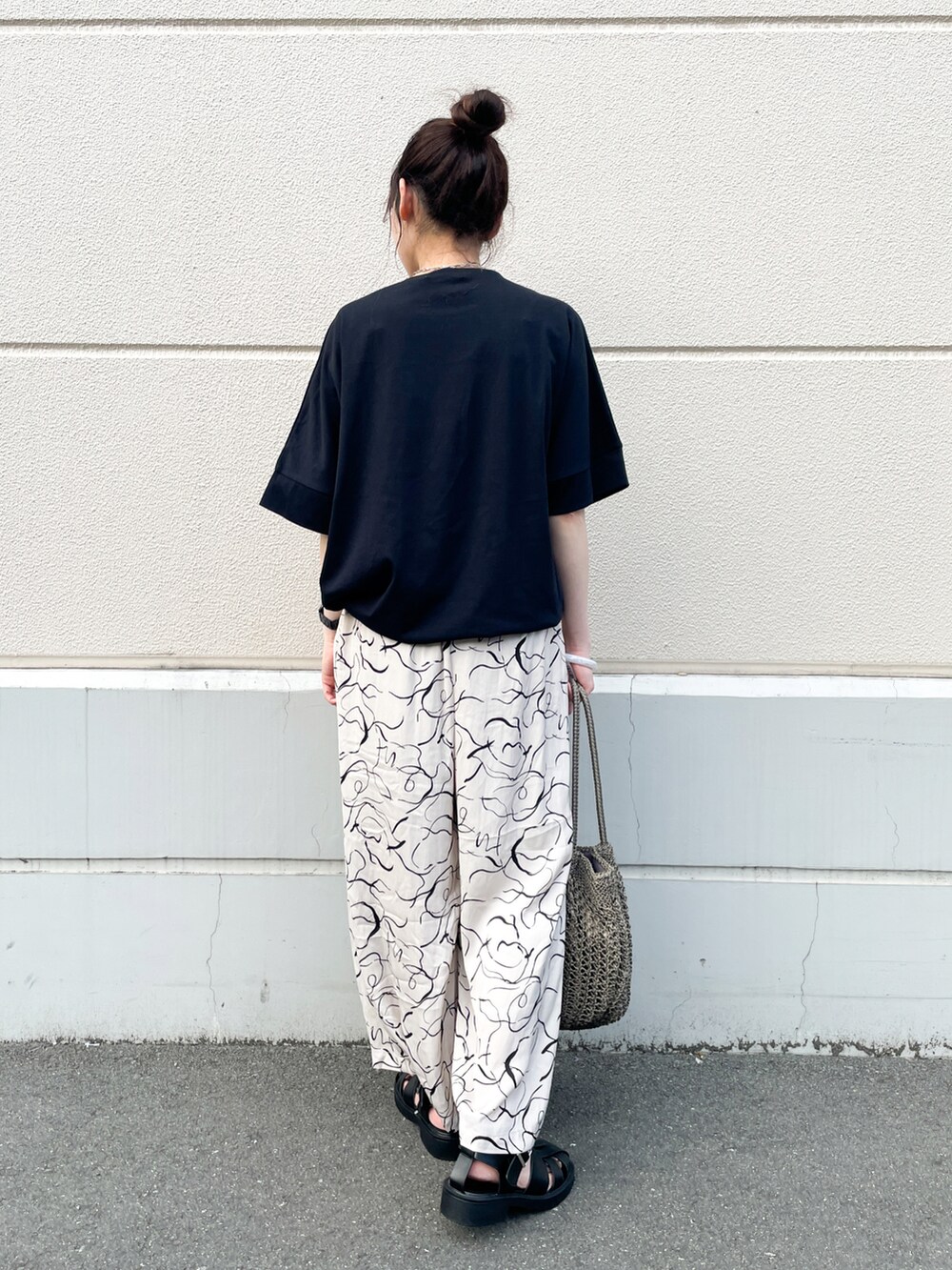 ベージュ系のその他パンツ、ブラック系のサンダル、ブラウン系のトートバッグを着用したレディースの夏コーディネートの3枚目の写真