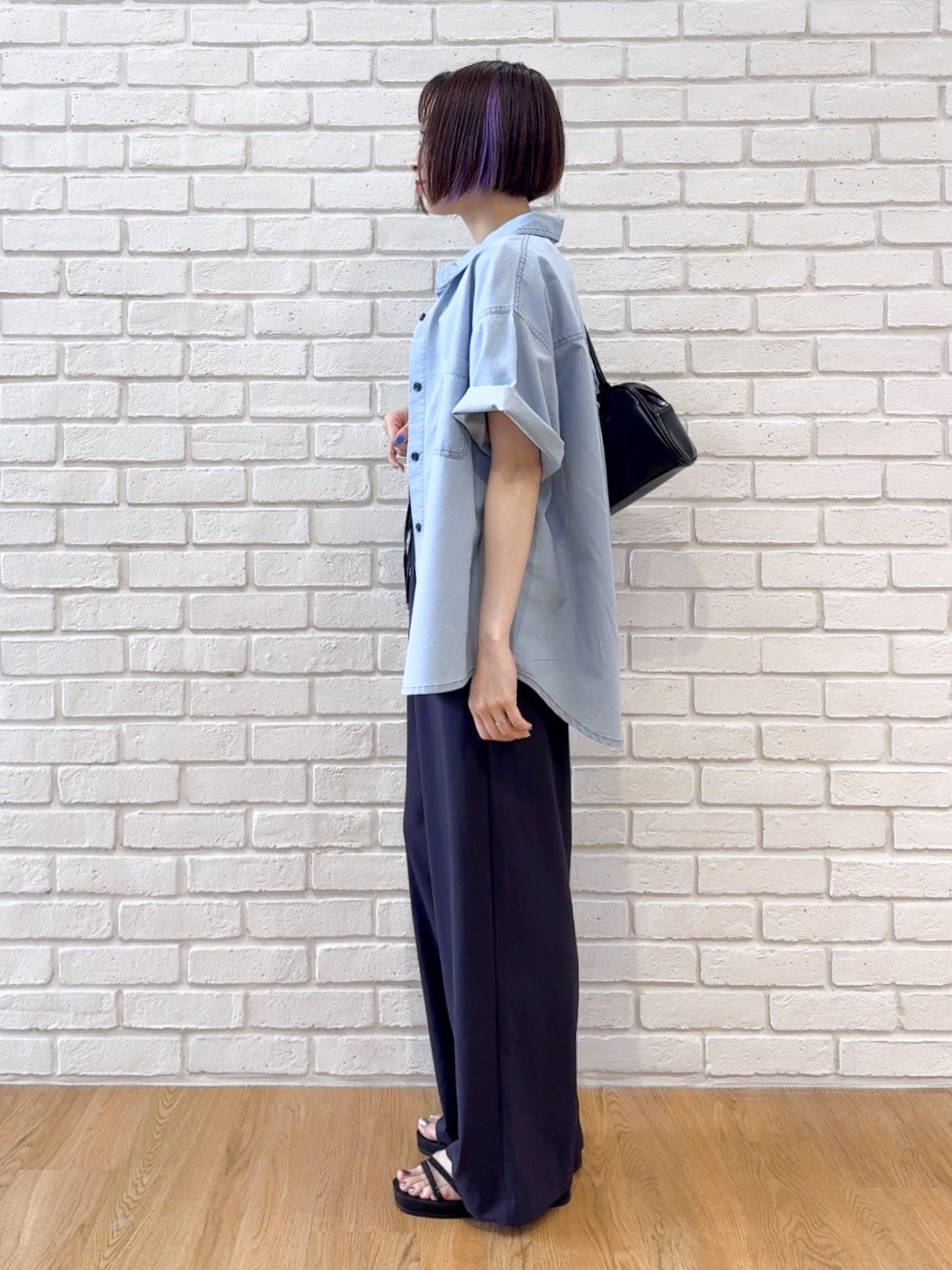 ブルー系のシャツ/ブラウス、ブラック系のサンダル、ブラック系のボストンバッグを着用したレディースの夏コーディネートの4枚目の写真