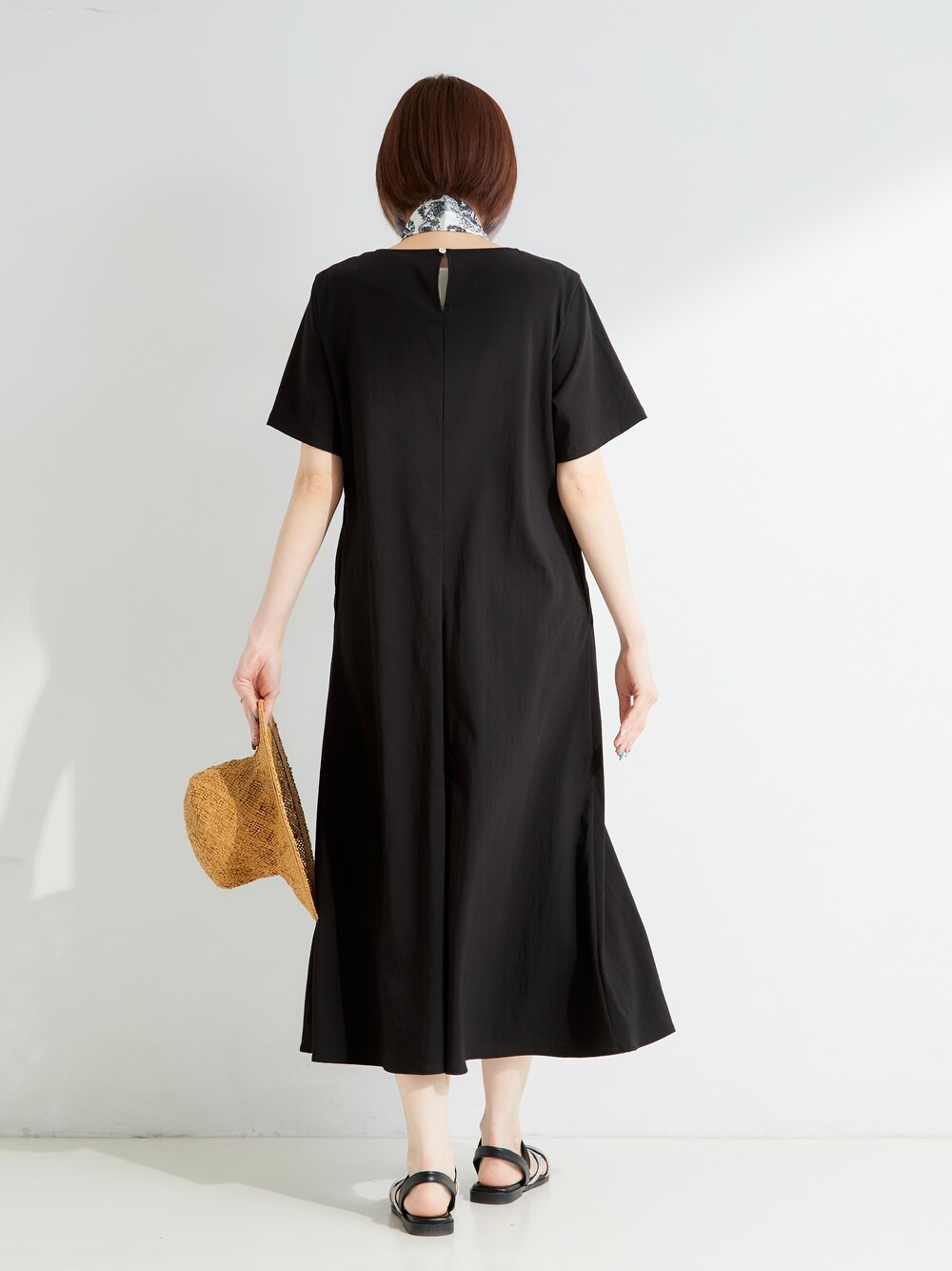 ブラック系のワンピース、ベージュ系のチャーム、イエロー系のハットを着用したレディースの夏コーディネートの3枚目の写真