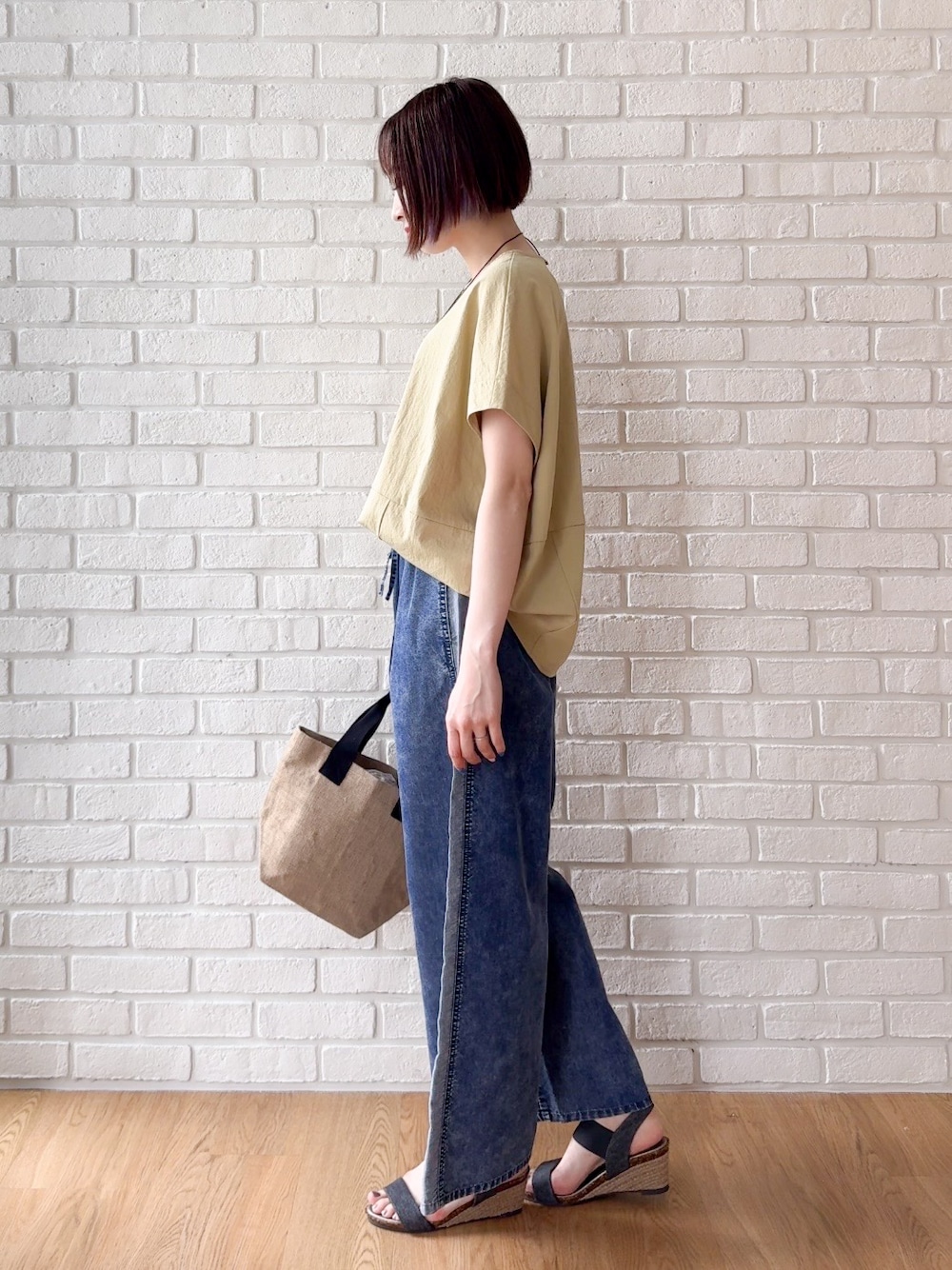 イエロー系のTシャツ/カットソー、ブルー系のデニムパンツ、ブラック系のサンダルを着用したレディースの夏コーディネートの4枚目の写真