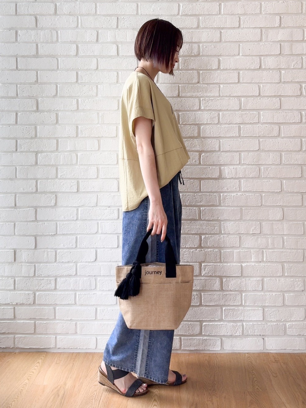 イエロー系のTシャツ/カットソー、ブルー系のデニムパンツ、ブラック系のサンダルを着用したレディースの夏コーディネートの2枚目の写真