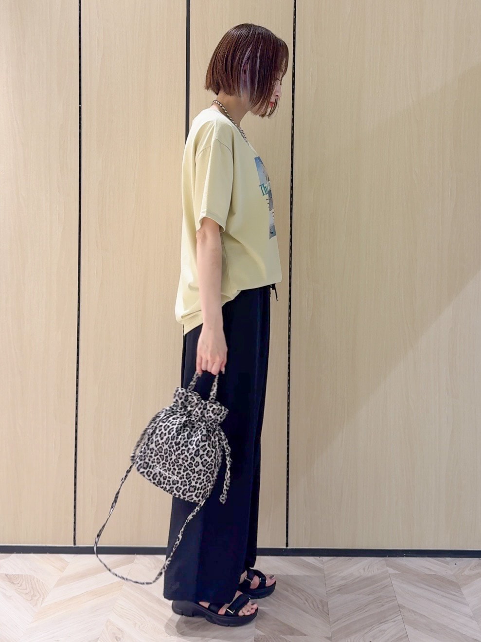 イエロー系のTシャツ/カットソー、ブラック系のサンダル、ベージュ系のショルダーバッグを着用したレディースの夏コーディネートの2枚目の写真