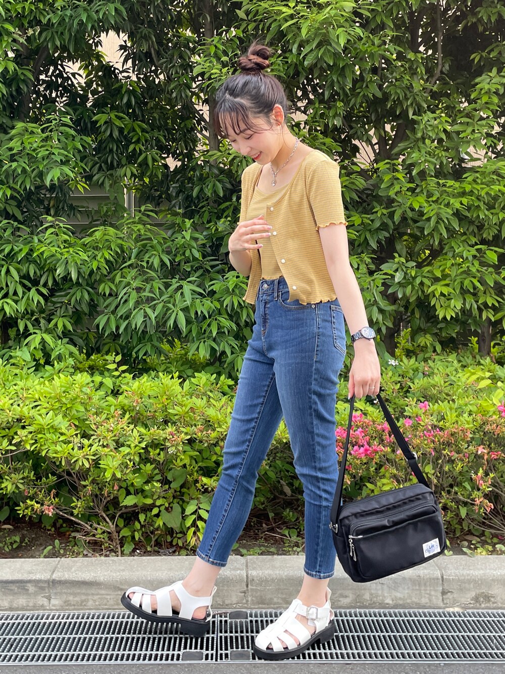イエロー系のアンサンブル、ブルー系のデニムパンツ、ホワイト系のサンダルを着用したレディースの夏コーディネートの2枚目の写真