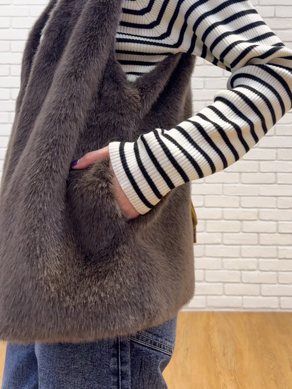 ブラウン系のベスト、ホワイト系のニット/セーター、ブルー系のデニムパンツを着用したレディースの秋コーディネートの5枚目の写真