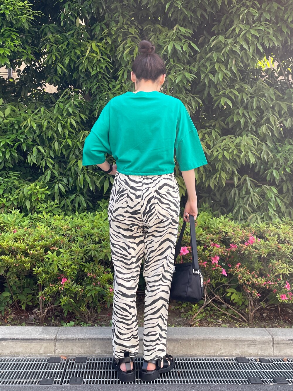 グリーン系のTシャツ/カットソー、ベージュ系のデニムパンツ、ブラック系のショルダーバッグを着用したレディースの夏コーディネートの3枚目の写真