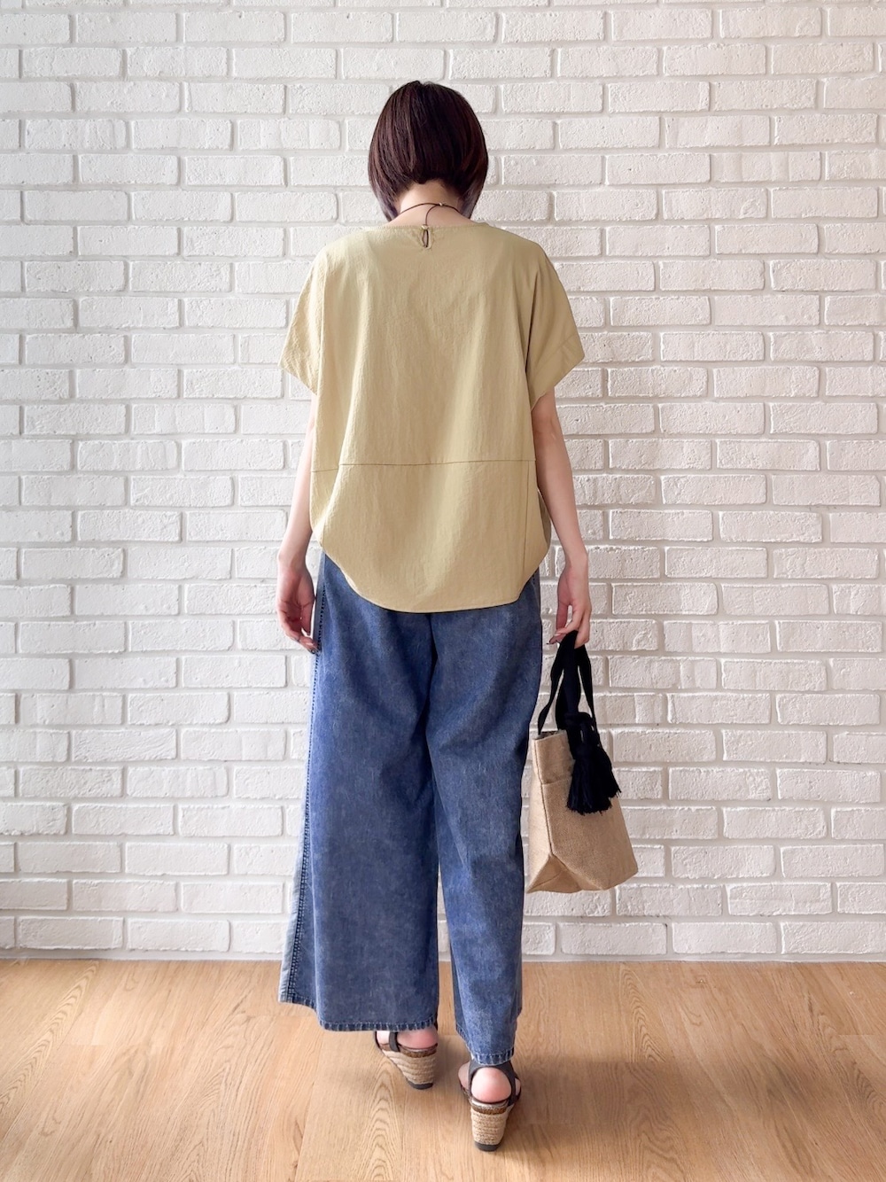 イエロー系のTシャツ/カットソー、ブルー系のデニムパンツ、ブラック系のサンダルを着用したレディースの夏コーディネートの3枚目の写真