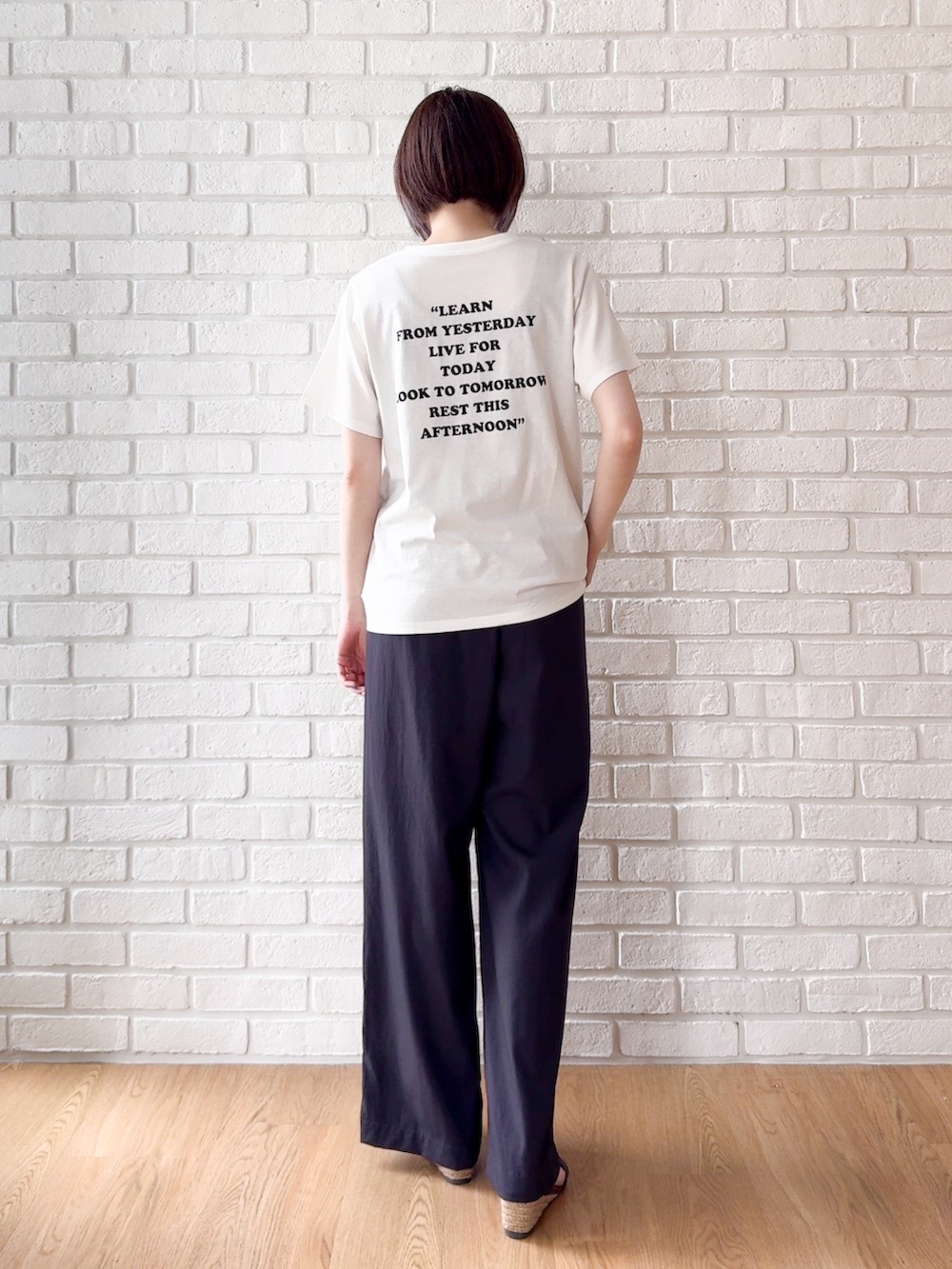 ホワイト系のTシャツ/カットソー、ブラック系のサンダル、ブラック系のトートバッグを着用したレディースの夏コーディネートの8枚目の写真