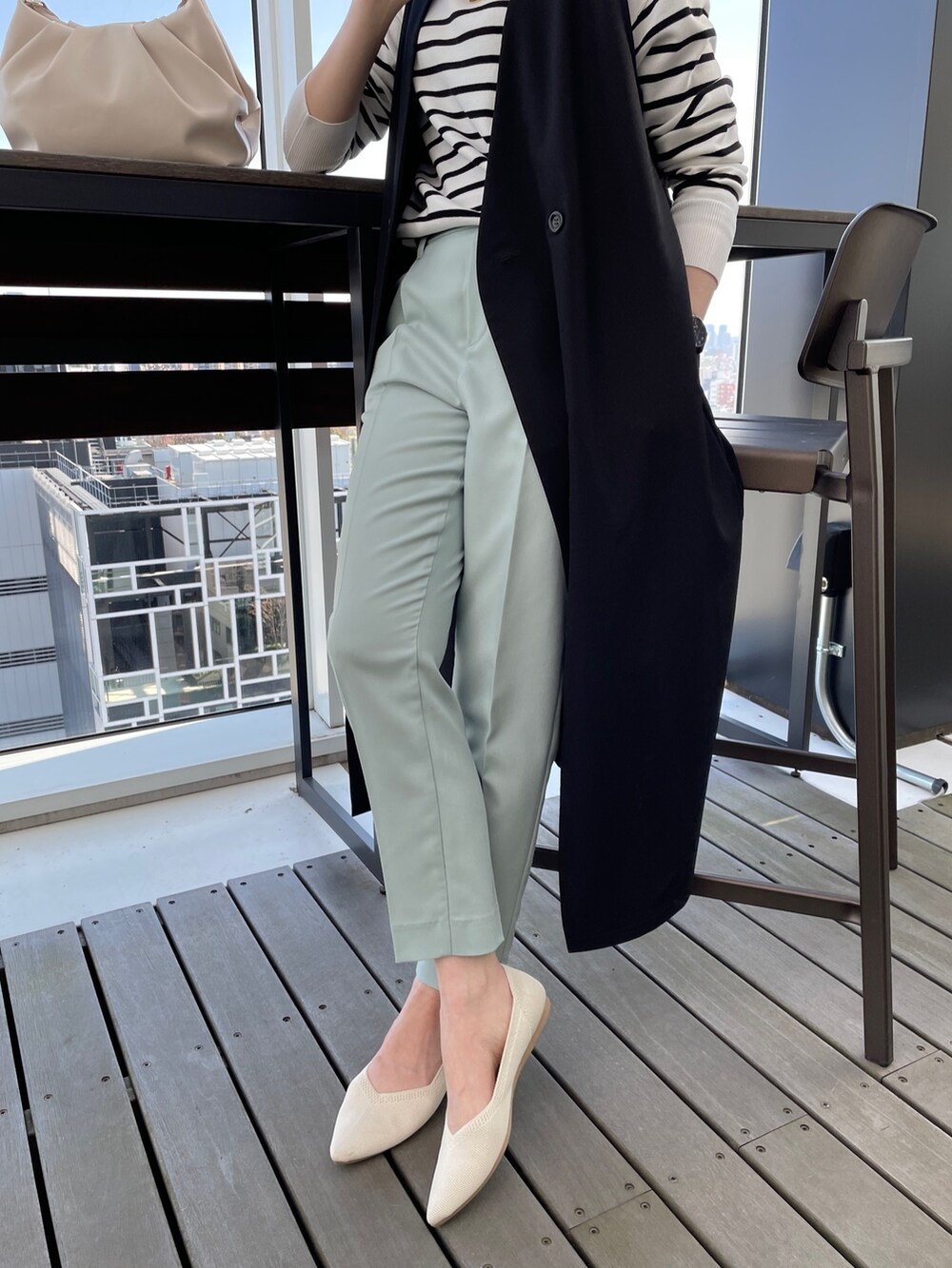 ブラック系のニット/セーター、ブラック系のベスト、ホワイト系のショルダーバッグを着用したレディースの春コーディネートの2枚目の写真