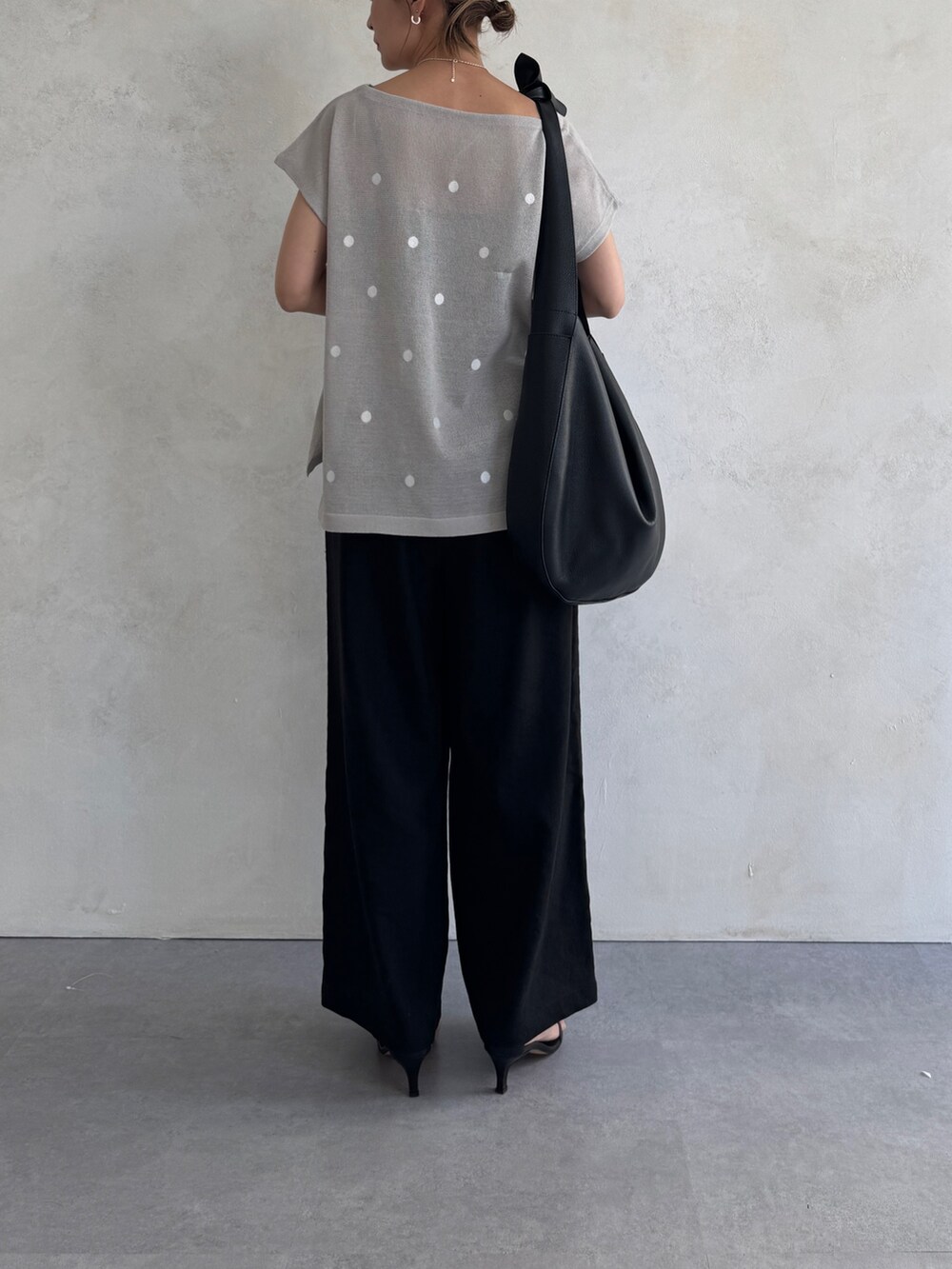 グレー系のニット/セーター、ブラック系のトートバッグ、ブラック系のその他パンツを着用したレディースの春コーディネートの2枚目の写真