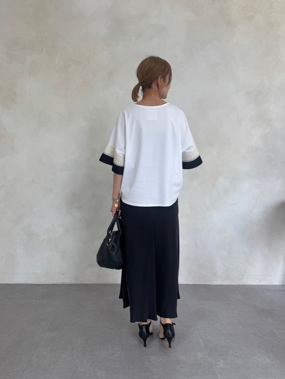 ホワイト系のTシャツ/カットソー、ブラック系のスカート、ブラック系のボストンバッグを着用したレディースの春コーディネートの2枚目の写真