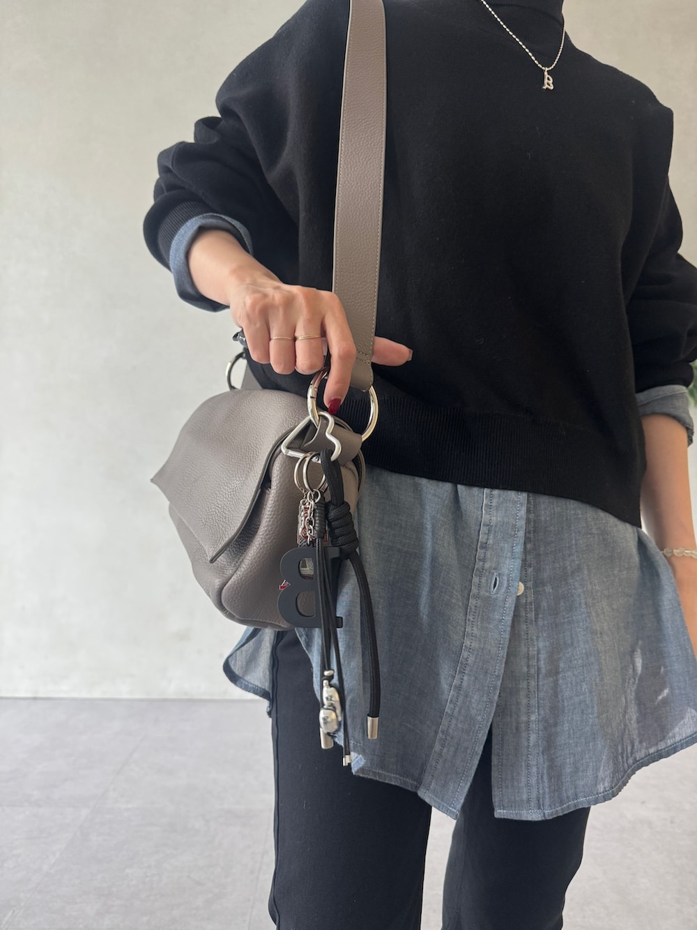 ブラック系のニット/セーター、ブルー系のシャツ/ブラウス、グレー系のショルダーバッグを着用したレディースの冬コーディネートの2枚目の写真