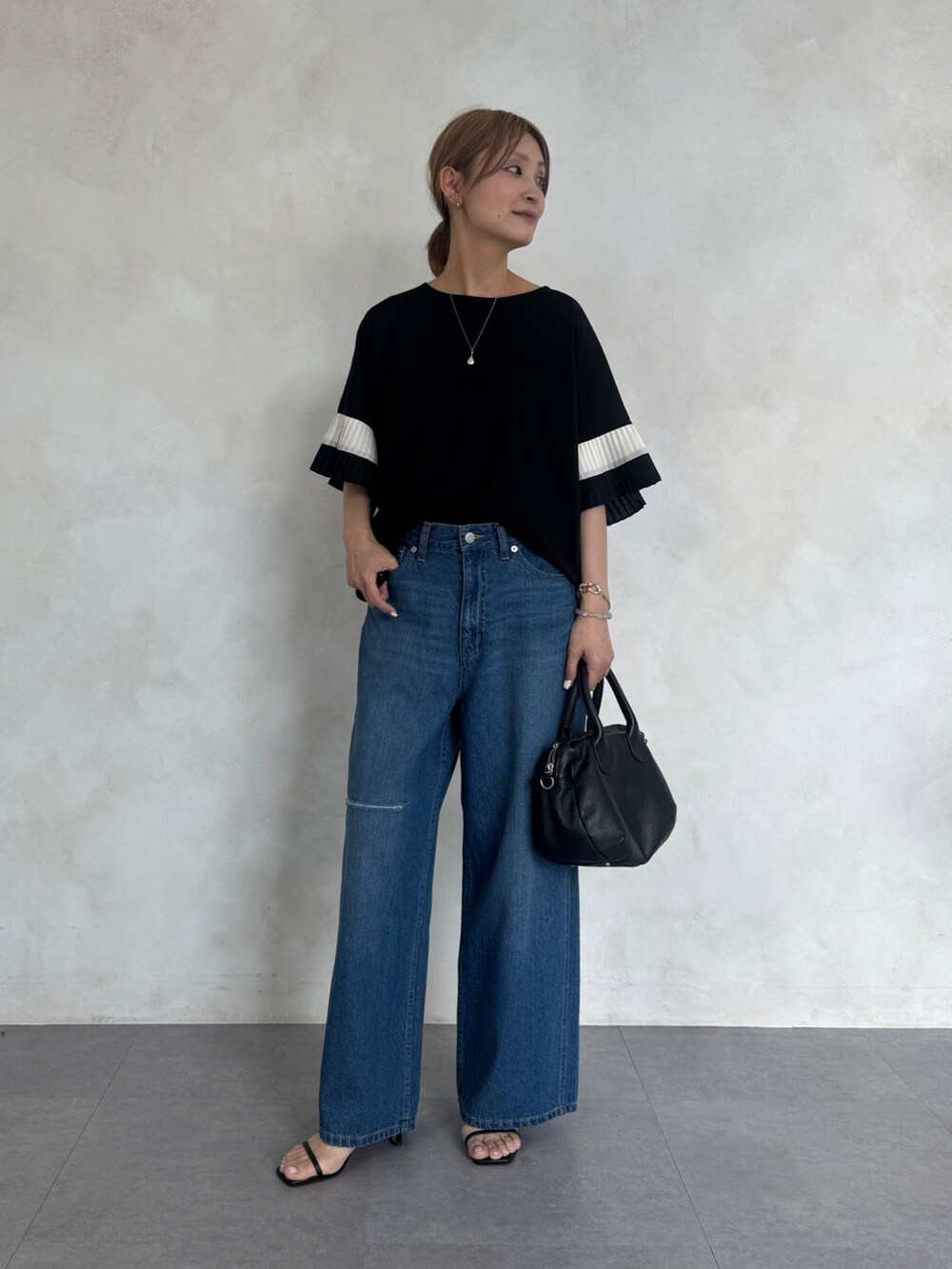 ブラック系のTシャツ/カットソー、ブルー系のその他パンツ、ブラック系のボストンバッグを着用したレディースの春コーディネートの4枚目の写真