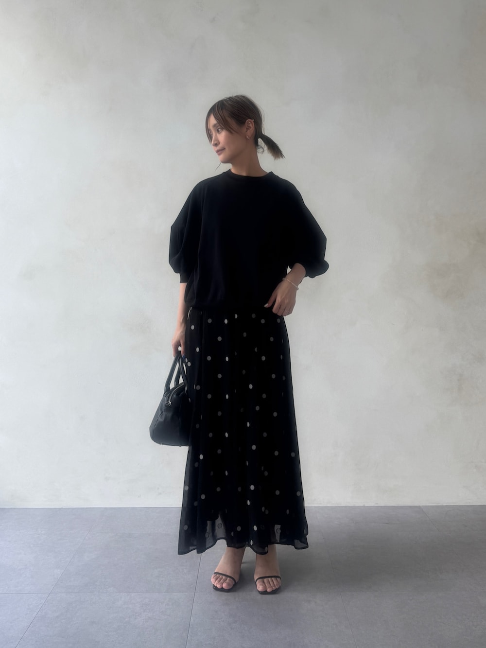 ブラック系のTシャツ/カットソー、ブラック系のスカート、ブラック系のボストンバッグを着用したレディースの冬コーディネートの2枚目の写真