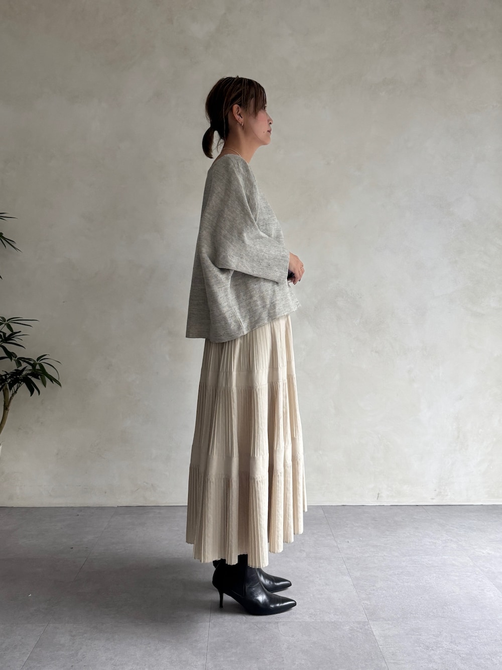 グレー系のニット/セーター、ホワイト系のスカートを着用したレディースの春コーディネートの2枚目の写真